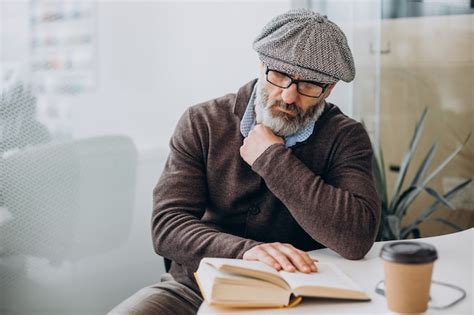 Hombre Barbudo Leyendo Un Libro Y Sentado A La Mesa Foto Gratis