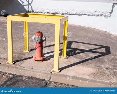 Yellow Rectangular Metal Structure Protecting A Fire Hydrant Stock