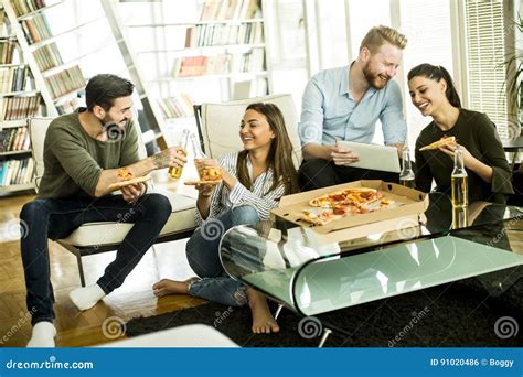 Grupo De Gente Joven Que Come La Pizza En El Cuarto Foto De Archivo