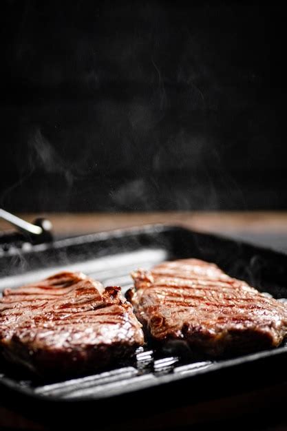 Premium Photo | Cooking grilled steak in a frying pan with hot steam