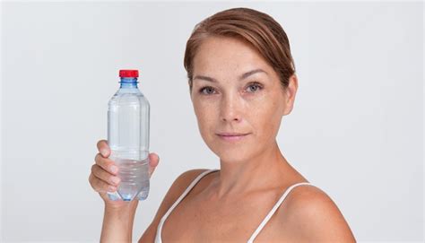 Mujer sosteniendo una botella de agua de plástico sobre fondo blanco