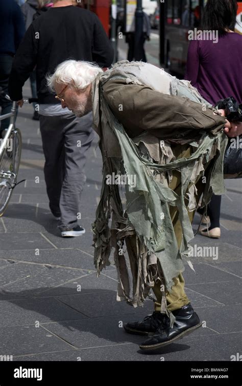 Down-and-out tramp/hobo wearing very ragged clothing in the centre of ...