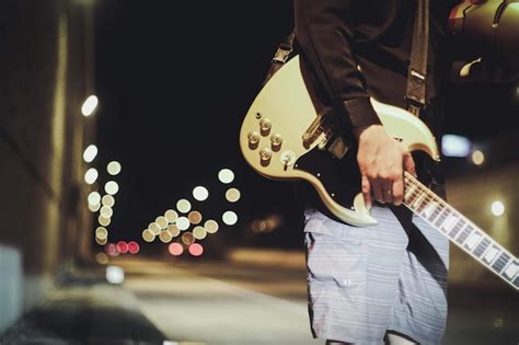 Premium Photo Midsection Of Man Holding Guitar While Standing On Road