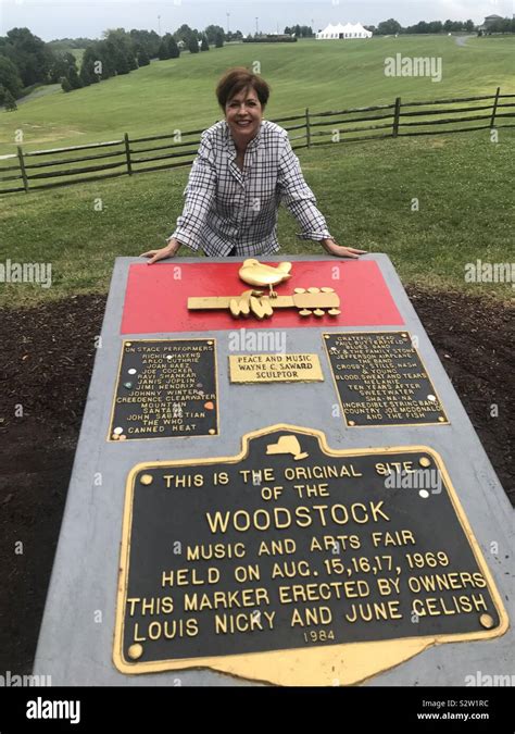 Woman stands being the Woodstock Memorial marker in Bethel, NY. Behind ...