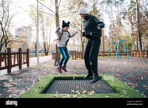 Mom And Her Daughter Jumping Together On Trampoline In Autumn Park