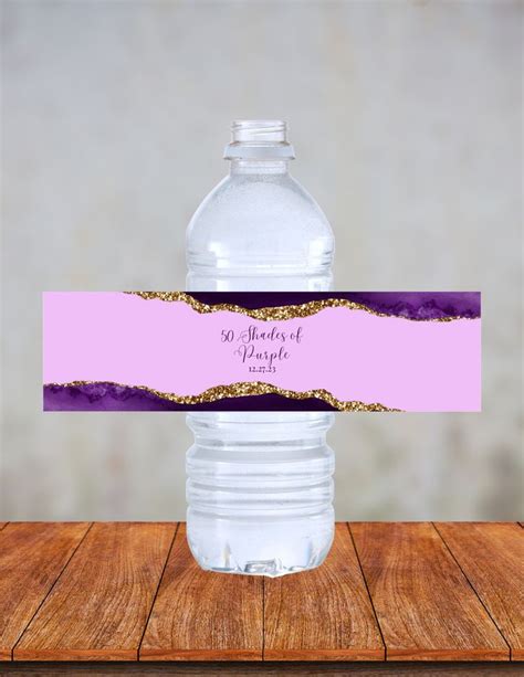 A Water Bottle With A Purple And Gold Label On It Sitting On A Wooden Table