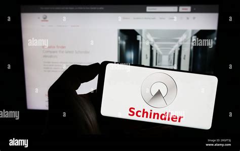 Person Holding Cellphone With Logo Of Swiss Elevator Company Schindler