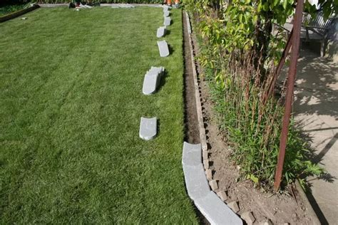 A Row Of Stone Benches Sitting On Top Of A Lush Green Field Next To A