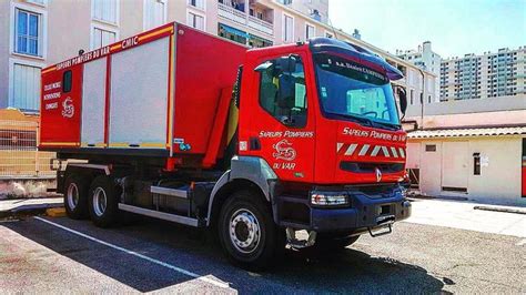 A Red Truck Is Parked On The Side Of The Road In Front Of A Building