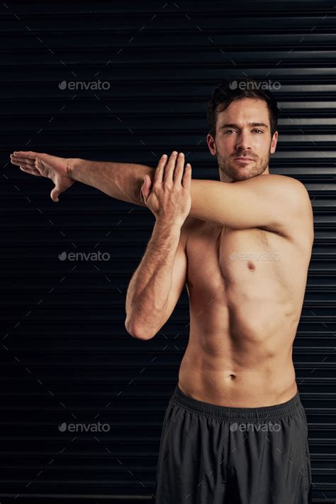 Studio Portrait Of A Shirtless And Well Built Man Warming Up Against A