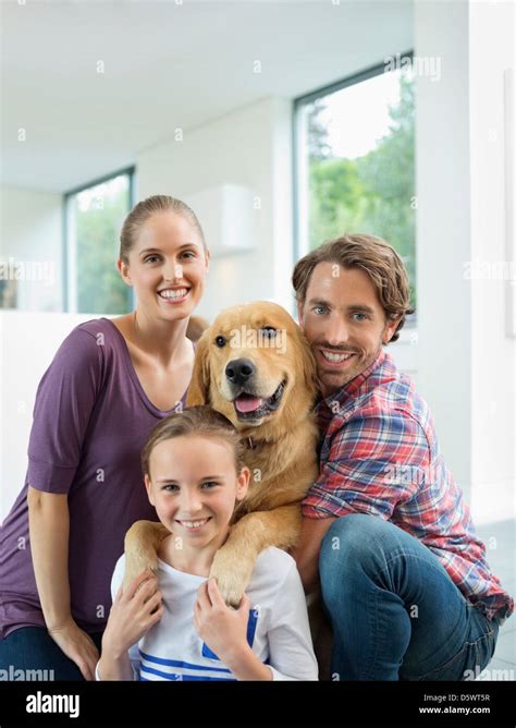 Family smiling with dog indoors Stock Photo - Alamy