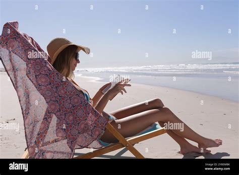 Caucasian Woman Wearing Bikini Sitting On Deck Chair Reading Book At The Beach Stock Photo Alamy