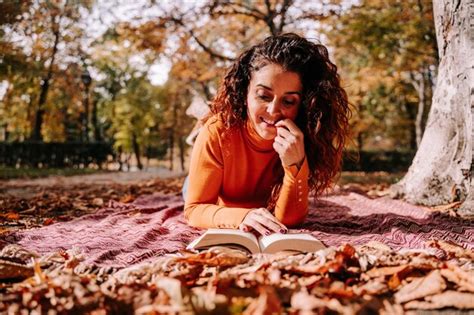 Mujer Sonriente Leyendo Un Libro Mientras Se Acuesta En El Parque