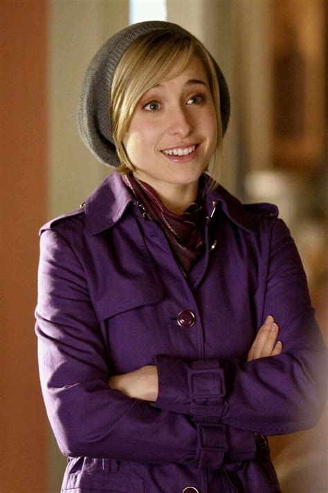 A Woman In A Purple Coat And Hat Is Standing With Her Arms Crossed