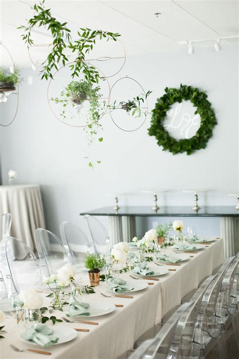 The Table Is Set Up With White Flowers And Greenery For An Elegant