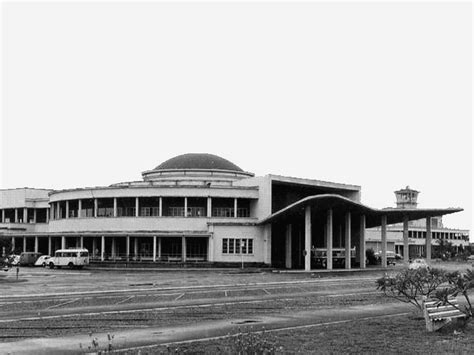 Black And White Photograph Of An Old Building With Cars Parked In Front