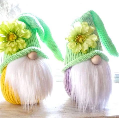 Two Gnomes With Flowers On Their Heads Sitting Next To Each Other In