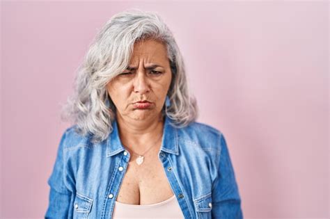 Mujer De Mediana Edad Con Cabello Gris De Pie Sobre Un Fondo Rosado