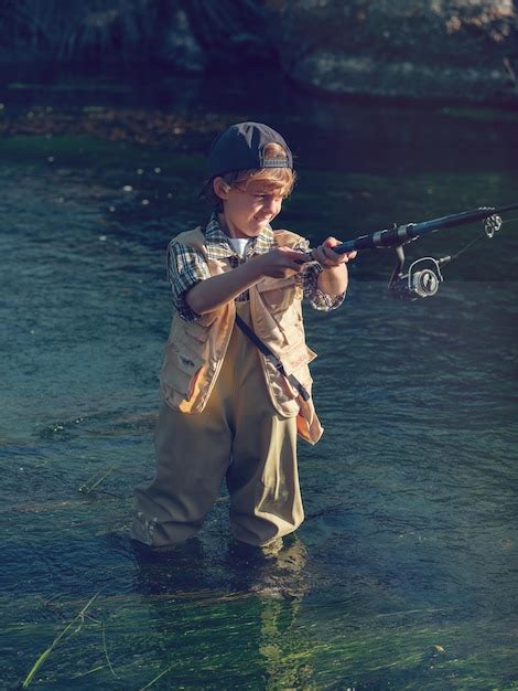 Premium Photo | Focused little fisher fishing in river