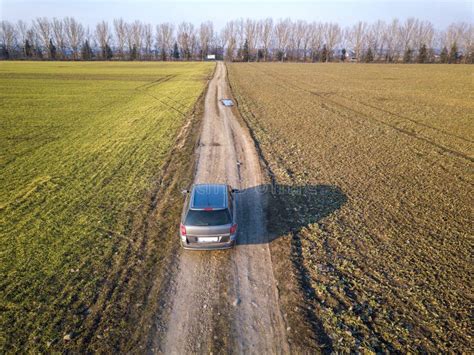 Aerial View Of Car Driving By Straight Ground Road Through Green Stock