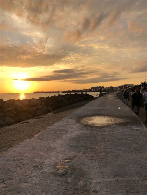 People Are Walking Along The Beach At Sunset