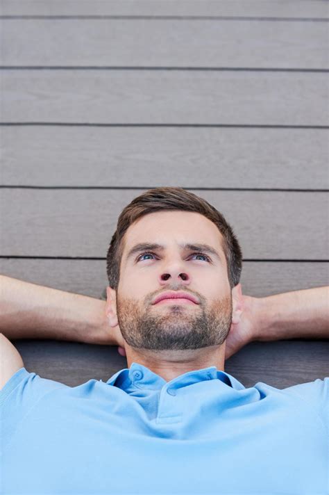 Man daydreaming. Top view of thoughtful young man holding hands behind ...