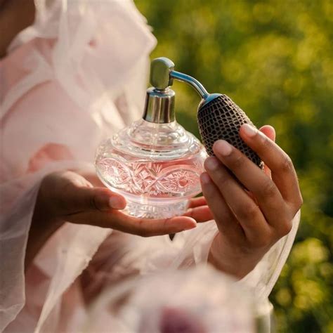 A Woman Holding A Perfume Bottle In Her Hands