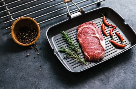 Premium Photo Raw Rib Eye Beef Steak On Black Grilling Pan With Chili