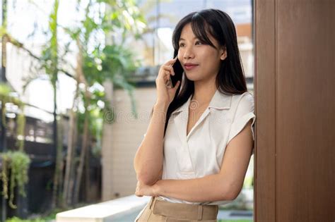 An Attractive Businesswoman Is Leaning Against The Building Wall