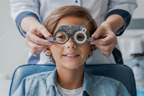 Premium Photo Smiling Child Boy In Glasses Checks Eye Vision At