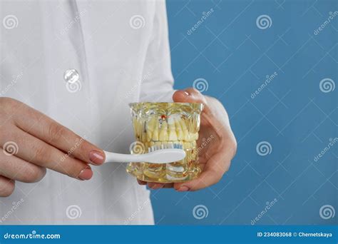 Dentist With Jaws Model And Toothbrush On Light Blue Background