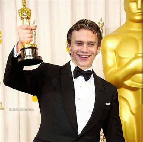 a man in a tuxedo holding an oscar statue