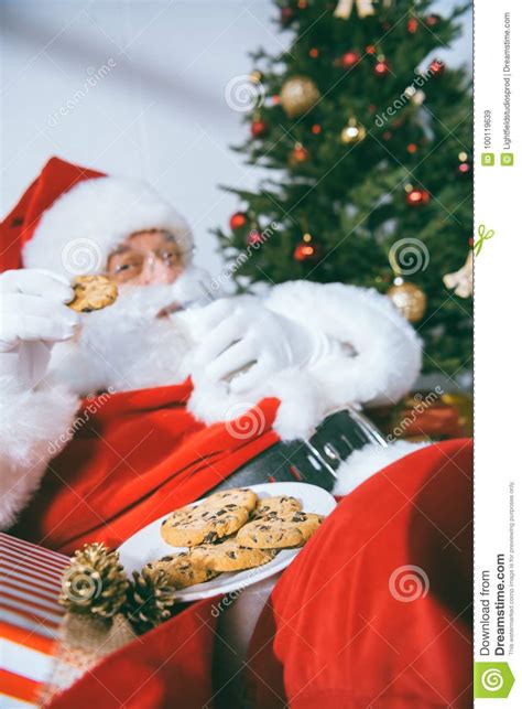 Santa claus eating cookies stock image. Image of indoors - 100119639