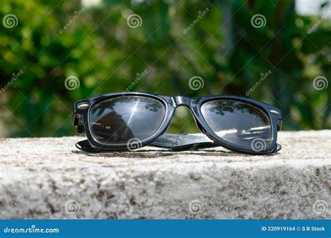 Black Sunglasses With Summer Sunlight Reflection Placed On Wall Of A