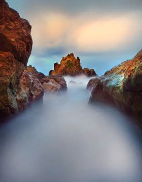 A Long Exposure Photo Of Rocks And Water At The End Of An Ocean Cliff Line