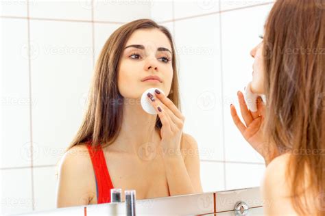 Young Beautiful Girl Standing Next To A Mirror And Wipes The Face With