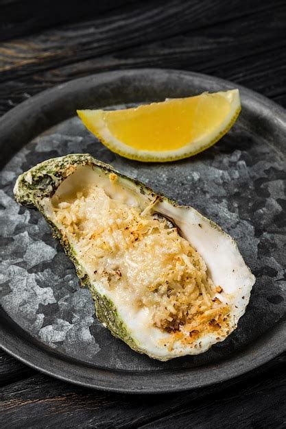 Premium Photo | Oyster baked with cheese served with lemon on a rustic ...