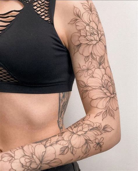 A Woman With Flowers On Her Arm And Chest Is Wearing A Black Bra Top