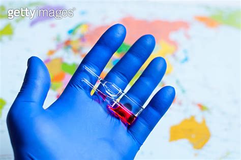 A Doctor S Hand In Blue Medical Glove Holding Ampoules With Vaccine