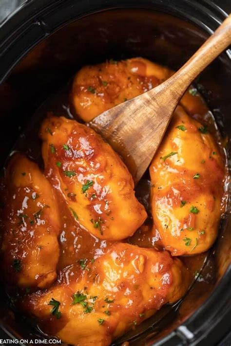 The Chicken Is Being Cooked In The Crock Pot With A Wooden Spoon On Top