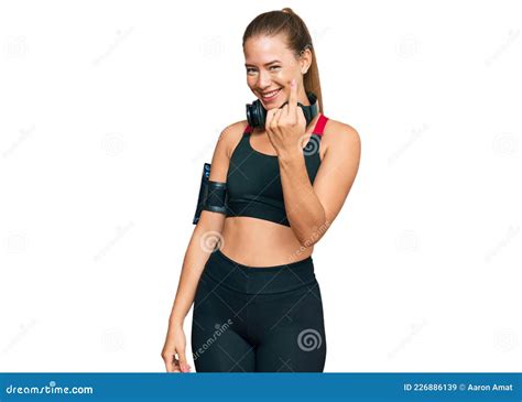 Beautiful Blonde Woman Wearing Gym Clothes And Using Headphones