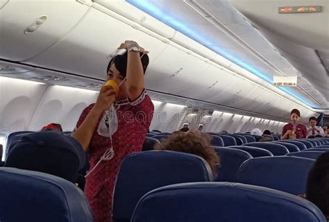 A Female Flight Attendants On The Aisle Show Passengers About Safety