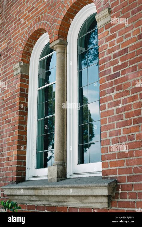 An Old Brick Building With Two Arched Windows During The Day Stock