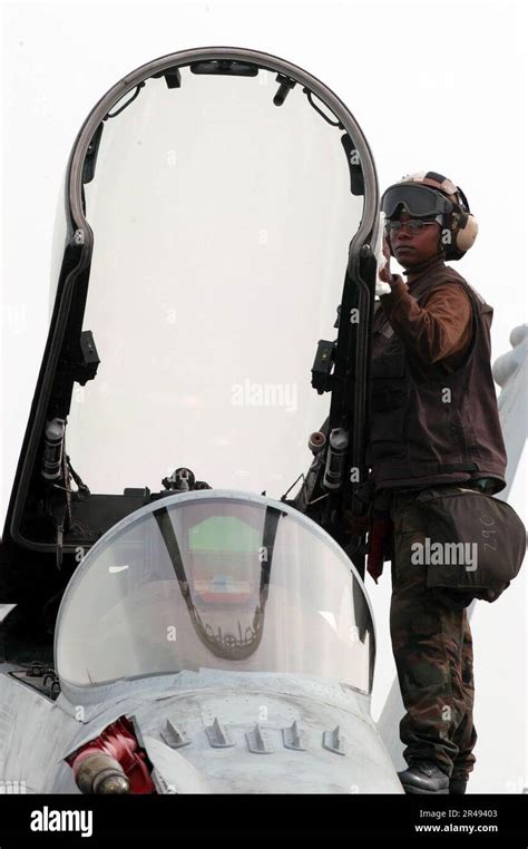 US Navy A Plane Captain Cleans A Canopy On An F 18 Hornet During