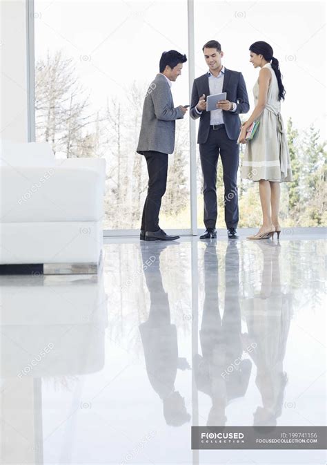 Business people talking at modern office — three people, window - Stock Photo | #199741156