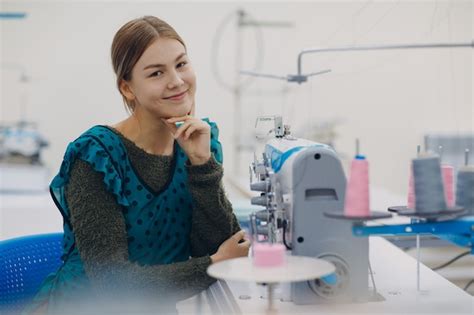 Costurera hermosa joven cose en la máquina de coser en la fábrica