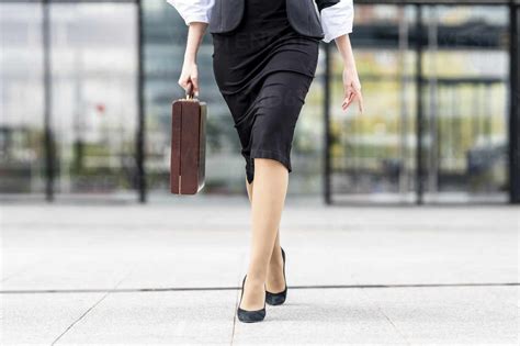 Young businesswoman wearing high heels walking with briefcase on ...