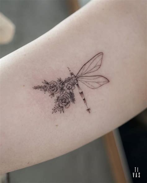 Floral dragonfly tattoo located on the inner arm.