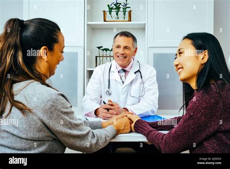 Smiling Doctor And Happy Adult Female Patients In Doctors Office