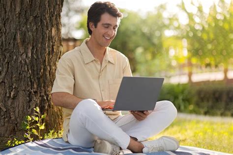 Sonriente hombre milenario freelancer trabajando en parque público